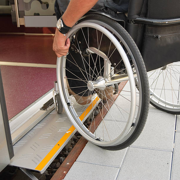 Low shot of a wheelchair user getting onto a train using the platform on his own.