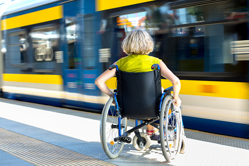 woman sitting on wheelchair on a platform with fast moving train in the background