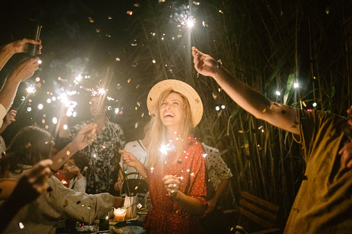 Photo of a young woman celebrating and having a summer dinner party with her family and friends.