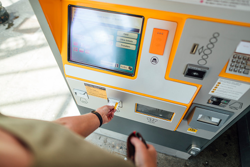 A close-up shot of an unrecognisable person collecting their ticket from a machine in a train station.