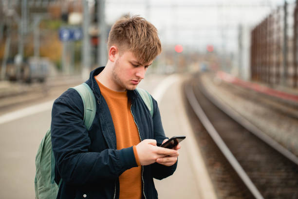 Young male adult using his smartphone while waiting for a train