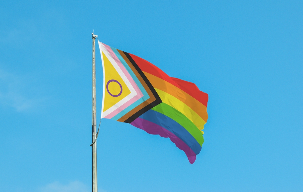 The Pride flag against a bright blue sky.