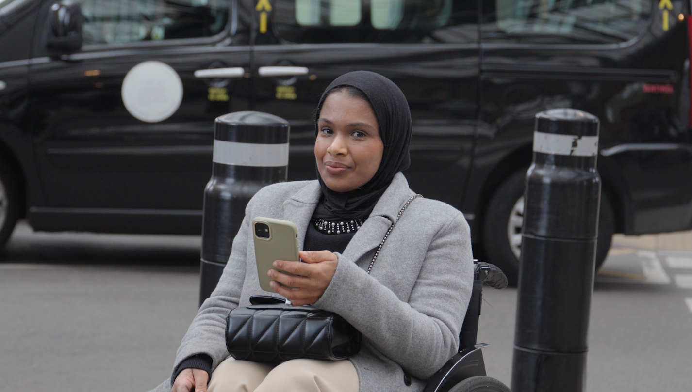 Umaymah, a Disabled wheelchair user, using her phone while travelling by train with Passenger Assistance.