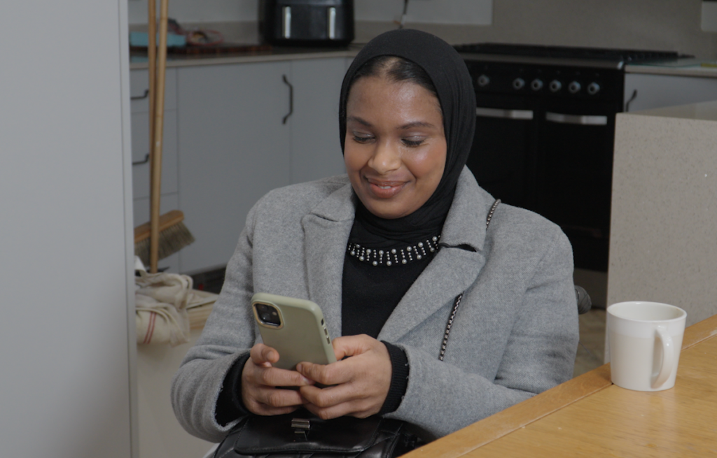 Umaymah, a Disabled wheelchair user, using her phone while planning a train journey with Passenger Assistance.