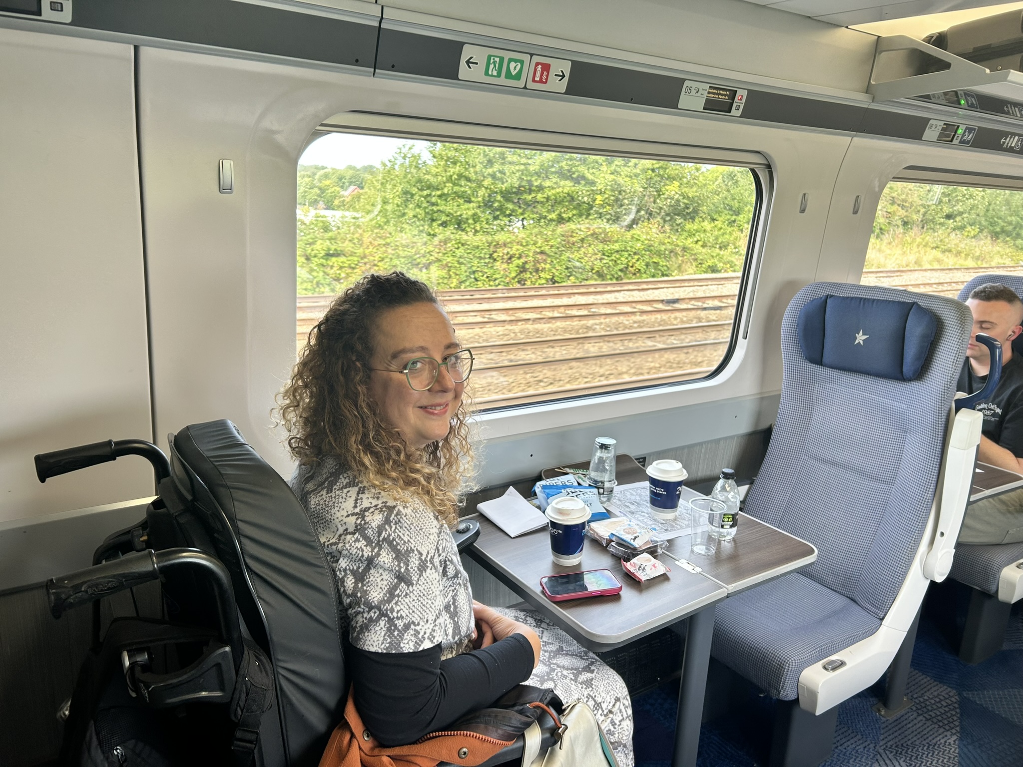 Carrie Ann Lightley smiling in the wheelchair space on a train during an accessible train journey.