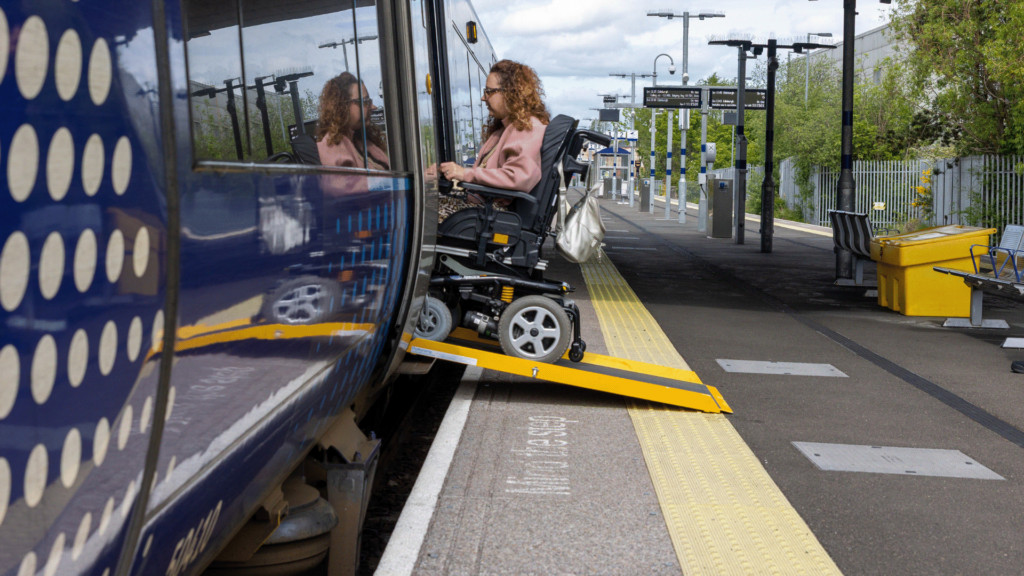 Carrie Ann Lightley using a ramp to board a train in her wheelchair.