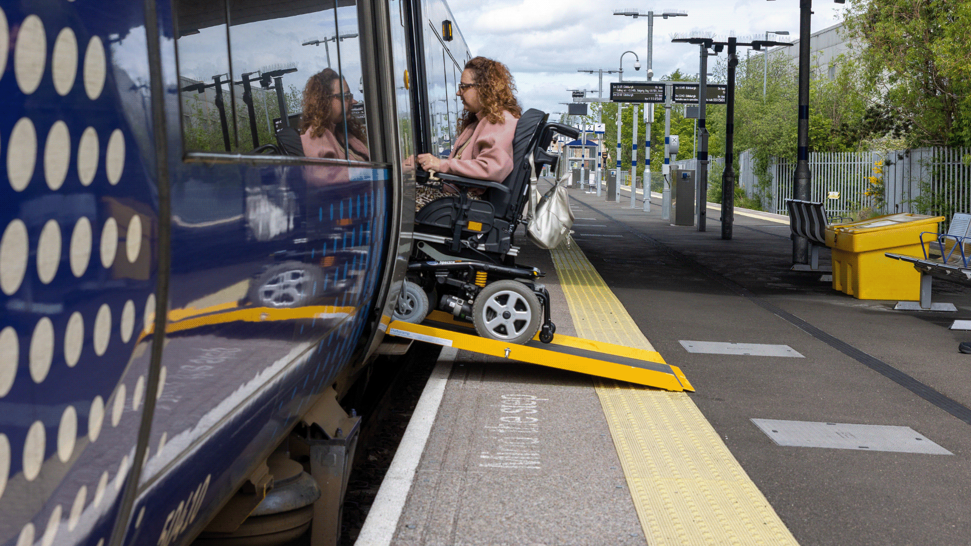 Carrie Ann Lightley using a ramp to board a train in her wheelchair.