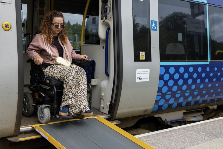 A wheelchair user getting off the train using a ramp