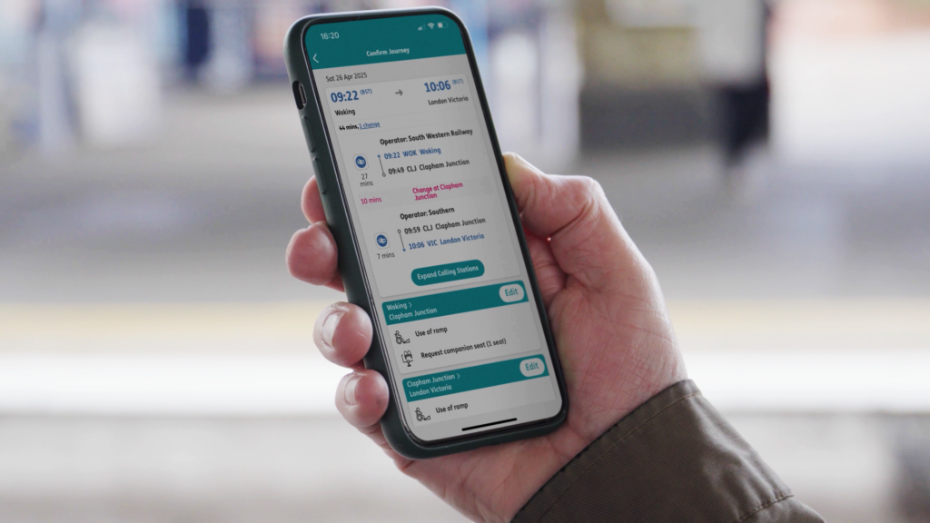 A male hand holding a phone displaying a confirmed journey in the Passenger Assistance app